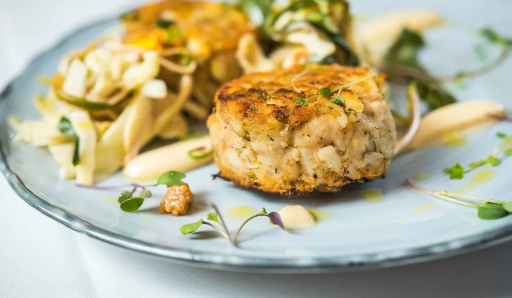 watershed Up close view of a crab cake on a dinner plate from Watershed Restaurant